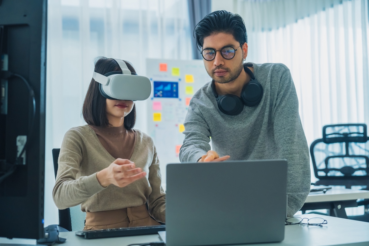 two people training in an office environment with one wearing a virtual reality headset.